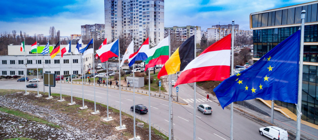 Cars driving down a motorway lined with various European flags to promote Car Insurance and Green Cards by Evalee Insurance brokers